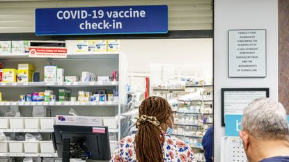 People stand in line at a Walgreens pharmacy counter offering Covid-19 vaccines.